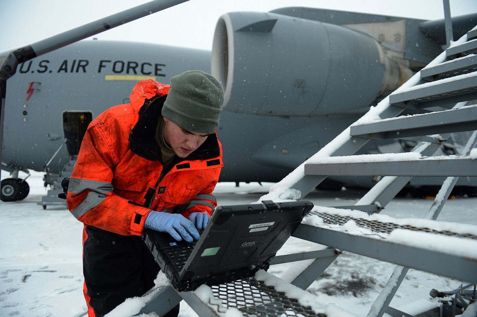 A hydraulics technician references a technical order on his laptop before working on a C-17